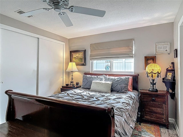 bedroom with a textured ceiling, wood finished floors, a closet, and a ceiling fan