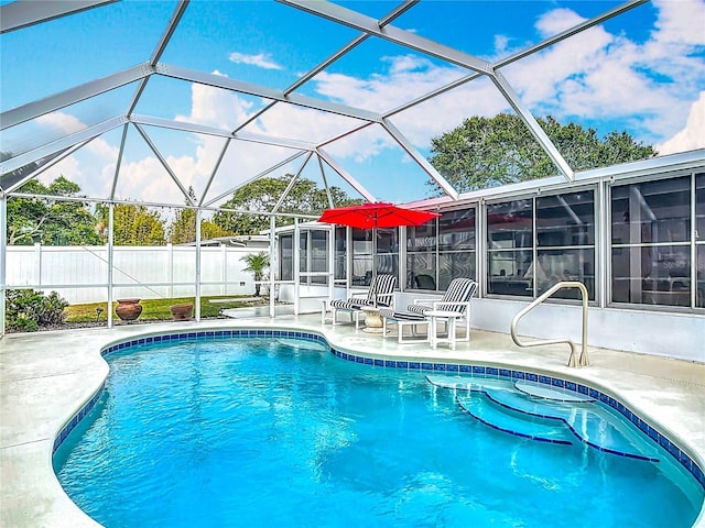 view of pool with a patio, fence, and glass enclosure