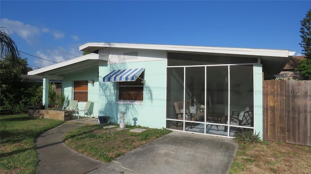 rear view of house featuring fence and a sunroom