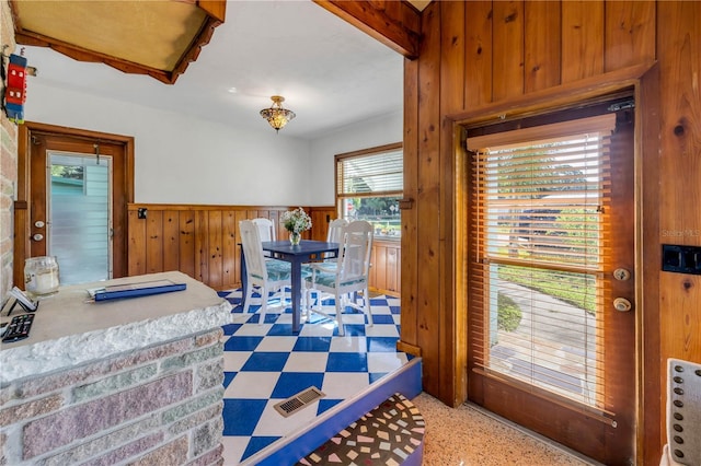 dining room featuring wainscoting, light flooring, and wooden walls