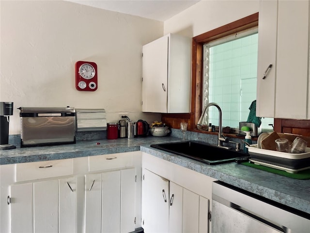 kitchen with a sink, stainless steel dishwasher, and white cabinets