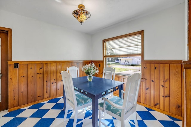 dining area featuring light flooring, wainscoting, and wood walls