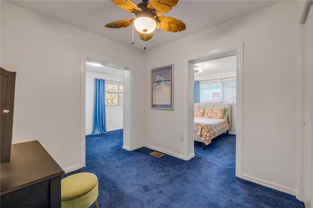 hall featuring dark colored carpet, healthy amount of natural light, and baseboards
