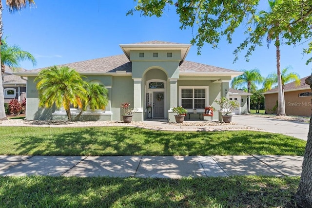 637 Marisol Dr, New Smyrna Beach, FL 32168 - mediterranean / spanish home featuring stucco siding, a front lawn, roof with shingles, and concrete driveway