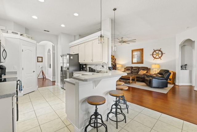 637 Marisol Dr, New Smyrna Beach, FL 32168 - kitchen featuring arched walkways, appliances with stainless steel finishes, light tile patterned floors, a ceiling fan, and a kitchen breakfast bar
