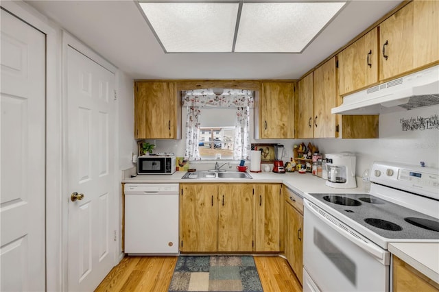 kitchen featuring white appliances, under cabinet range hood, a sink, and light countertops