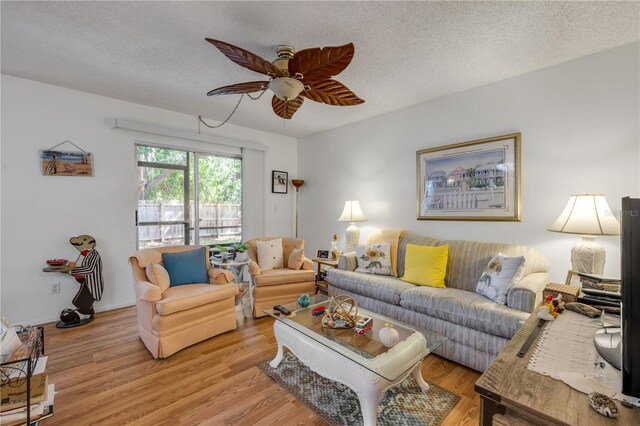 living room featuring a ceiling fan, a textured ceiling, and light wood-style flooring