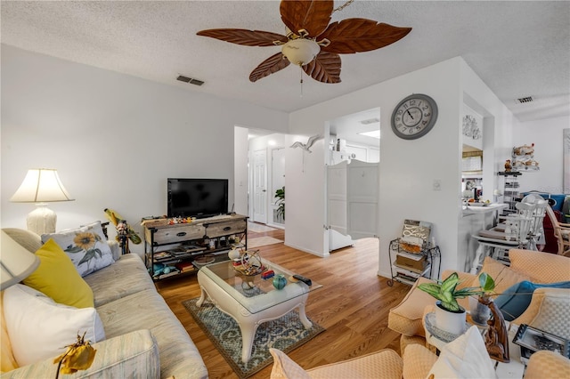living area with wood finished floors, ceiling fan, and a textured ceiling