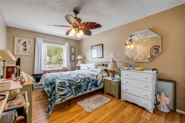 bedroom featuring a textured ceiling, light wood-style floors, and ceiling fan