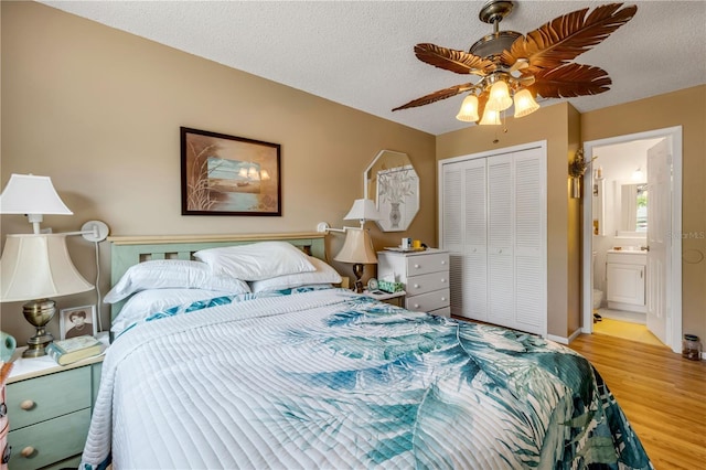 bedroom with wood finished floors, a closet, a textured ceiling, a ceiling fan, and ensuite bathroom