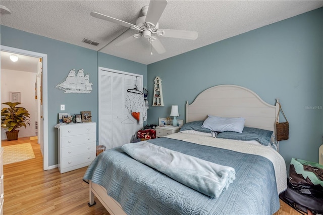 bedroom with wood finished floors, a closet, a textured ceiling, and a ceiling fan