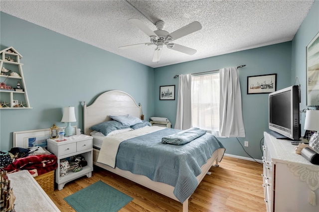 bedroom with light wood-style floors, a textured ceiling, a ceiling fan, and baseboards