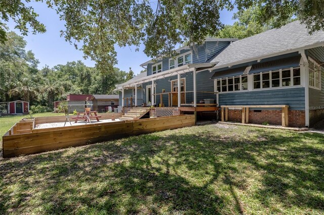 4580 Lake James Cir, Edgewater, FL 32141 - back of house featuring a wooden deck, a lawn, a shingled roof, and a shed
