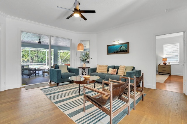 living area featuring ceiling fan, crown molding, light wood-style flooring, and baseboards