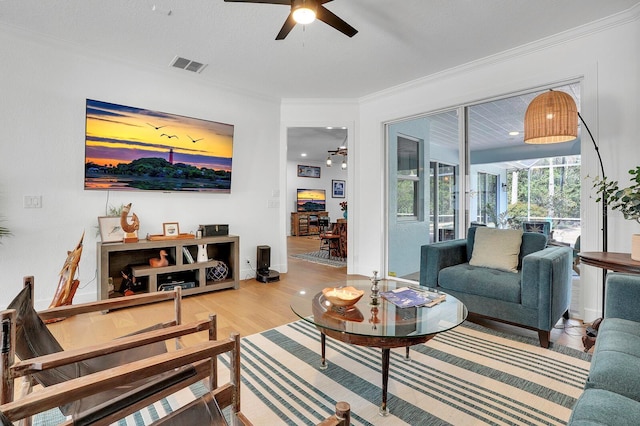 living room featuring a ceiling fan, ornamental molding, light wood-style flooring, and baseboards