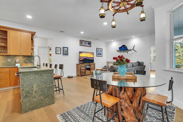 dining area featuring crown molding, light wood-style floors, recessed lighting, and baseboards