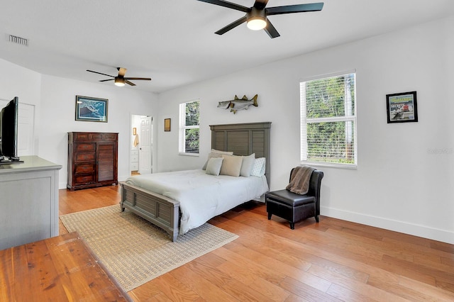 bedroom featuring multiple windows, light wood finished floors, baseboards, and a ceiling fan