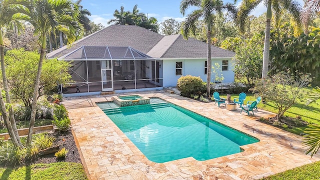 view of swimming pool featuring a patio, glass enclosure, a pool with connected hot tub, and an outdoor fire pit