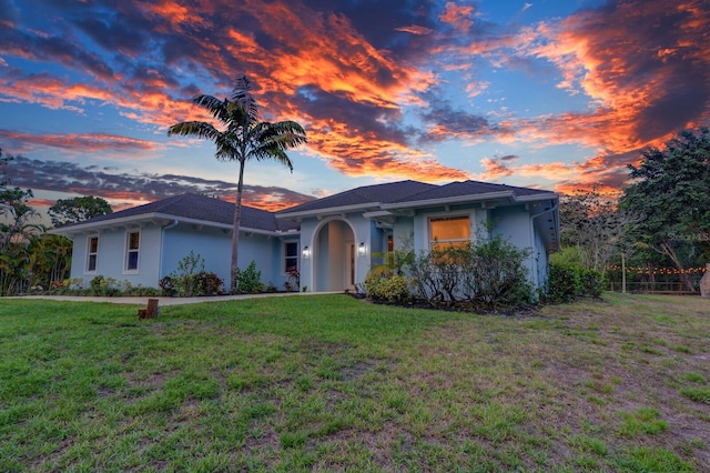 single story home with stucco siding and a front yard