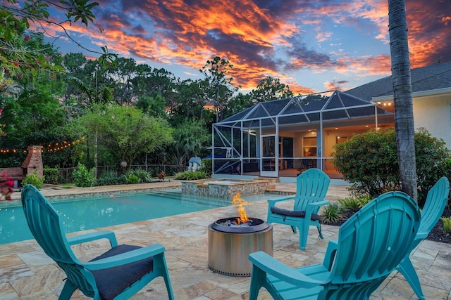 swimming pool featuring an in-ground hot tub, a patio, a fire pit, and glass enclosure
