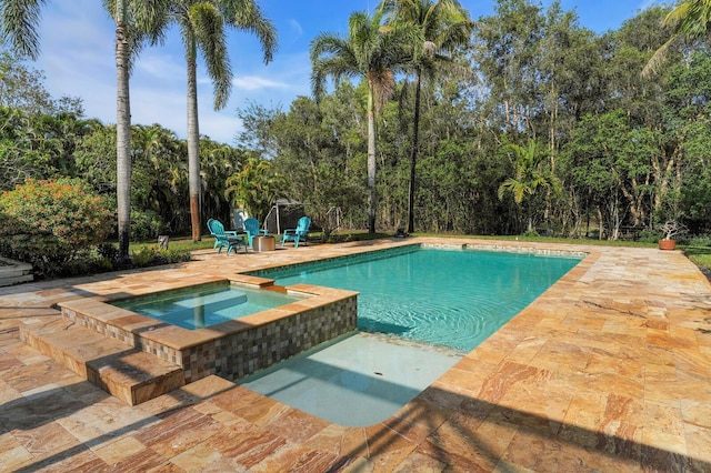 view of swimming pool featuring a patio area, a pool with connected hot tub, and view of scattered trees