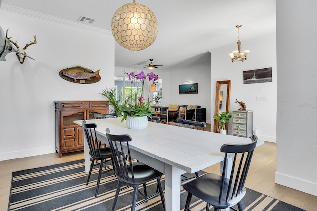 dining space with ceiling fan, a chandelier, baseboards, wood finished floors, and ornamental molding
