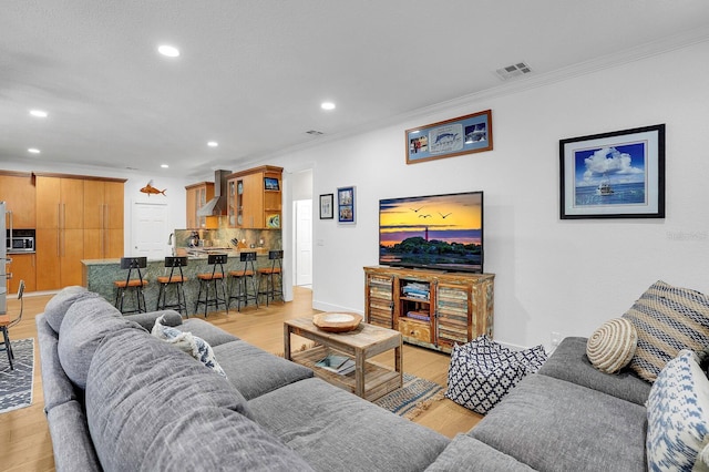 living area featuring recessed lighting, crown molding, light wood-style floors, and baseboards
