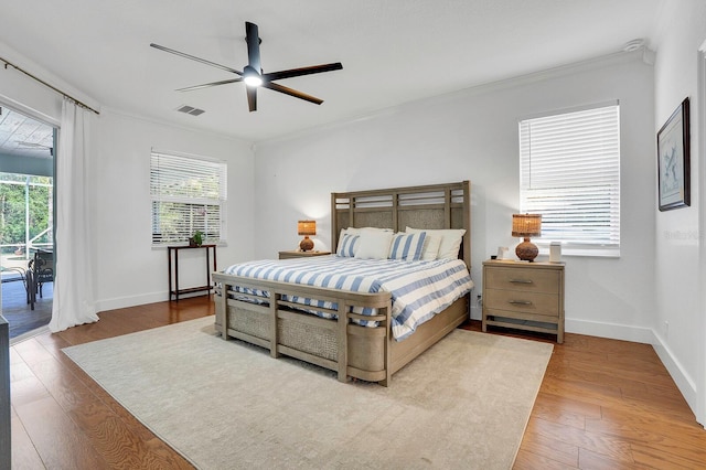 bedroom with access to exterior, crown molding, wood finished floors, and baseboards