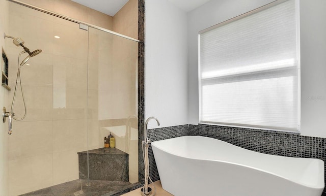 bathroom featuring a shower stall and a freestanding tub
