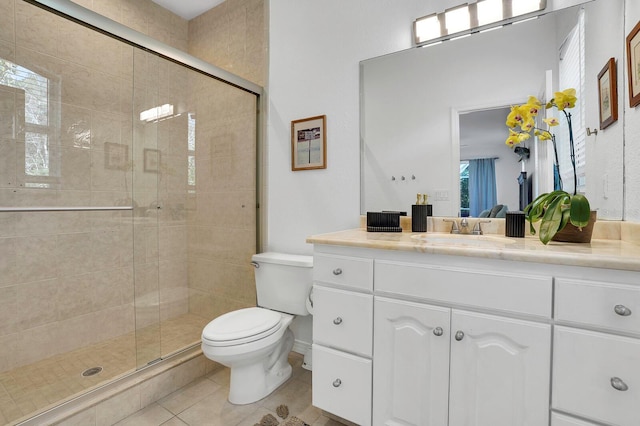 bathroom featuring toilet, tile patterned flooring, a shower stall, and vanity