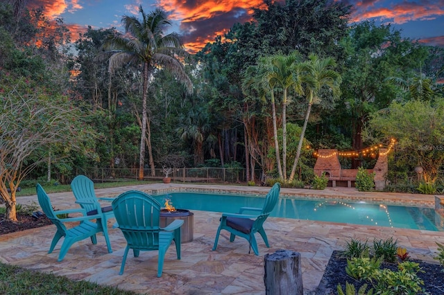 view of pool with a fire pit, a patio area, and fence