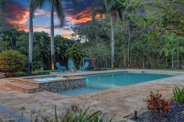 swimming pool with a patio and an in-ground hot tub