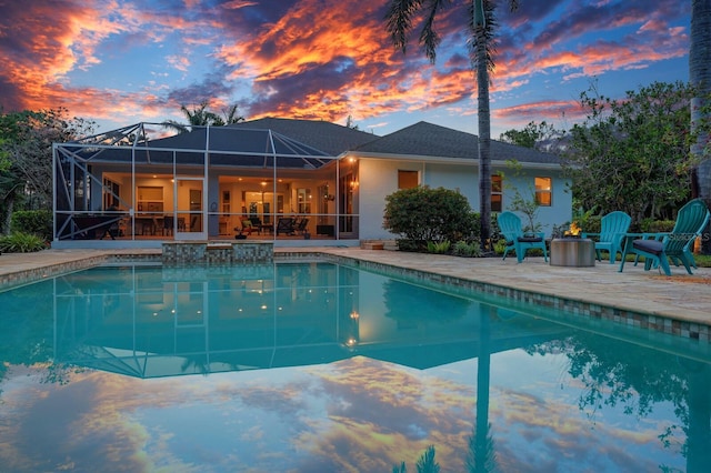 pool at dusk featuring a patio, a lanai, and an outdoor pool