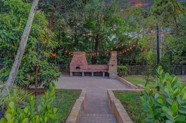 view of patio with an outdoor brick fireplace and fence