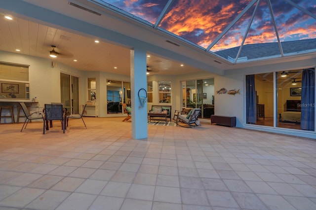 view of patio with a ceiling fan, glass enclosure, and outdoor dining area