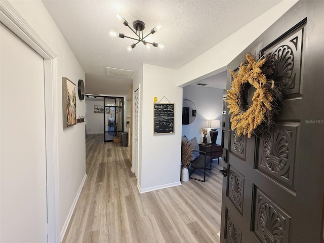208 Wellington Dr, Daytona Beach, FL 32119 - hallway with light wood-style flooring, a chandelier, baseboards, and a textured ceiling