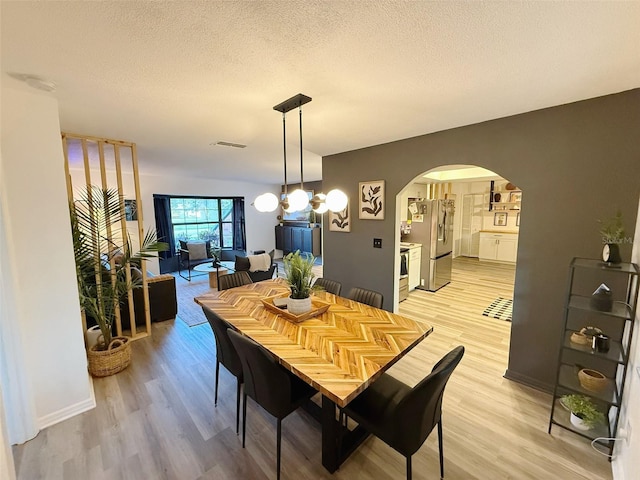 208 Wellington Dr, Daytona Beach, FL 32119 - dining space featuring arched walkways, light wood-style floors, and a textured ceiling