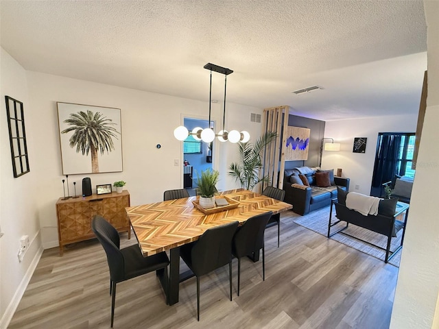 208 Wellington Dr, Daytona Beach, FL 32119 - dining room with light wood finished floors, a textured ceiling, baseboards, and a chandelier