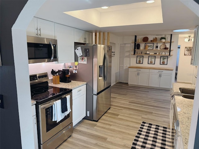 208 Wellington Dr, Daytona Beach, FL 32119 - kitchen with stainless steel appliances, a raised ceiling, white cabinets, light wood finished floors, and light stone countertops