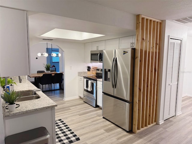 208 Wellington Dr, Daytona Beach, FL 32119 - kitchen featuring appliances with stainless steel finishes, light wood finished floors, a sink, white cabinetry, and baseboards