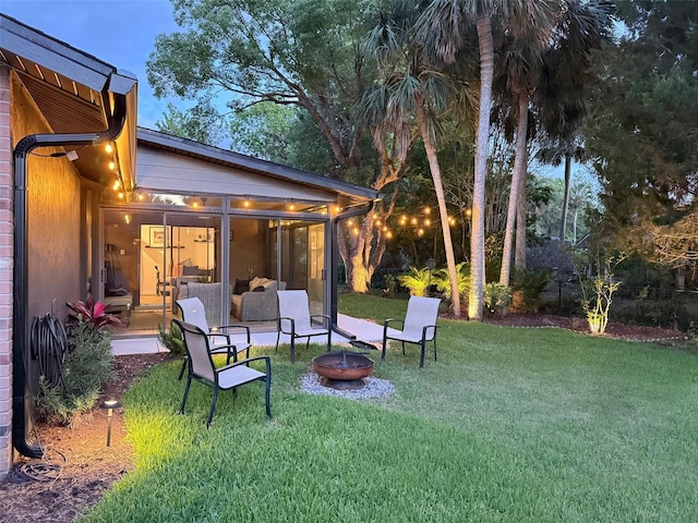 208 Wellington Dr, Daytona Beach, FL 32119 - view of grassy yard with a fire pit and a sunroom