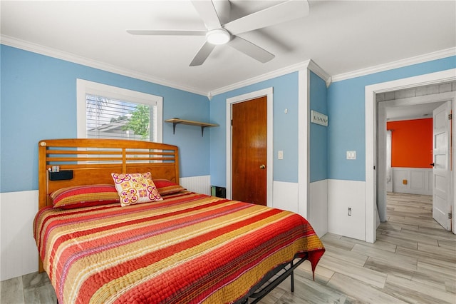 2576 Sunset Dr, New Smyrna Beach, FL 32168 - bedroom featuring crown molding, wainscoting, wood finished floors, and ceiling fan