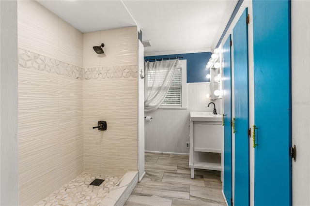 2576 Sunset Dr, New Smyrna Beach, FL 32168 - bathroom featuring tiled shower, vanity, and a wainscoted wall