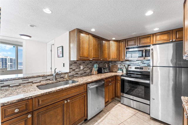 2625 S Atlantic Ave Unit 18Nw, Daytona Beach, FL 32118 - kitchen featuring stainless steel appliances, a sink, brown cabinets, tasteful backsplash, and light stone counters
