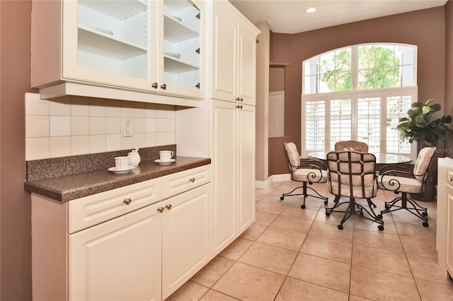 1442 Carlow Cir, Ormond Beach, FL 32174 - kitchen with dark countertops, glass insert cabinets, decorative backsplash, white cabinets, and light tile patterned floors