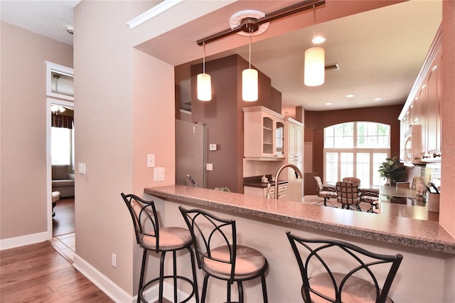 1442 Carlow Cir, Ormond Beach, FL 32174 - kitchen with wood finished floors, glass insert cabinets, white cabinets, a kitchen bar, and a peninsula