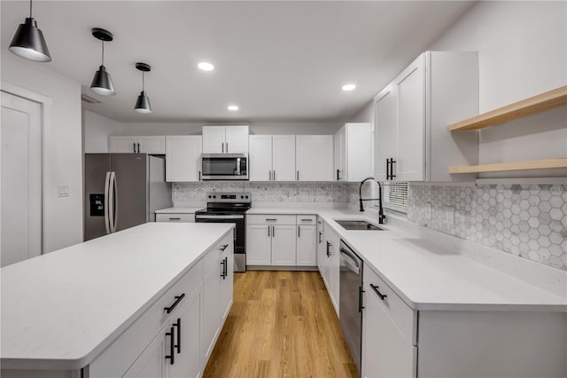 2822 Brookline Ave, New Smyrna Beach, FL 32168 - kitchen with appliances with stainless steel finishes, a sink, white cabinets, a kitchen island, and light wood-type flooring