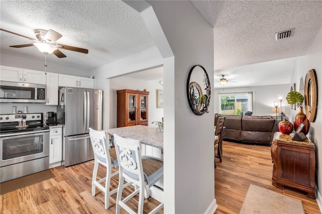 1205 Bond St, Edgewater, FL 32132 - kitchen featuring appliances with stainless steel finishes, a ceiling fan, a textured ceiling, white cabinetry, and open floor plan