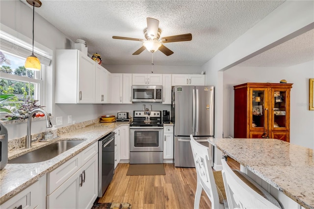 1205 Bond St, Edgewater, FL 32132 - kitchen featuring appliances with stainless steel finishes, a sink, a textured ceiling, white cabinetry, and light wood-style floors