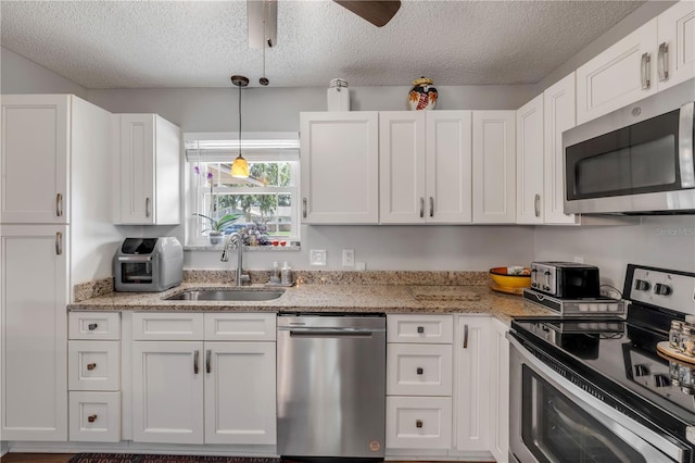 1205 Bond St, Edgewater, FL 32132 - kitchen with stainless steel appliances, a sink, a textured ceiling, white cabinets, and a ceiling fan